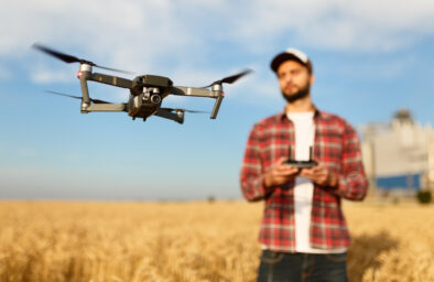 Compact drone hovers in front of farmer with remote controller in his hands. Quadcopter flies near pilot. Agronomist taking aerial photos and videos in a wheat fieldaRolnictwo 4.0.Co można kupić?