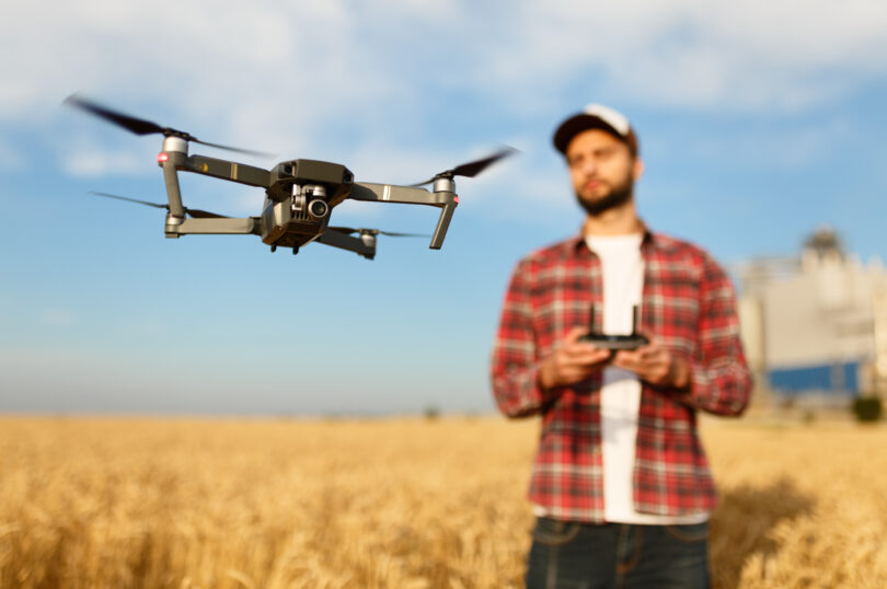 Compact drone hovers in front of farmer with remote controller in his hands. Quadcopter flies near pilot. Agronomist taking aerial photos and videos in a wheat fieldaRolnictwo 4.0.Co można kupić?
